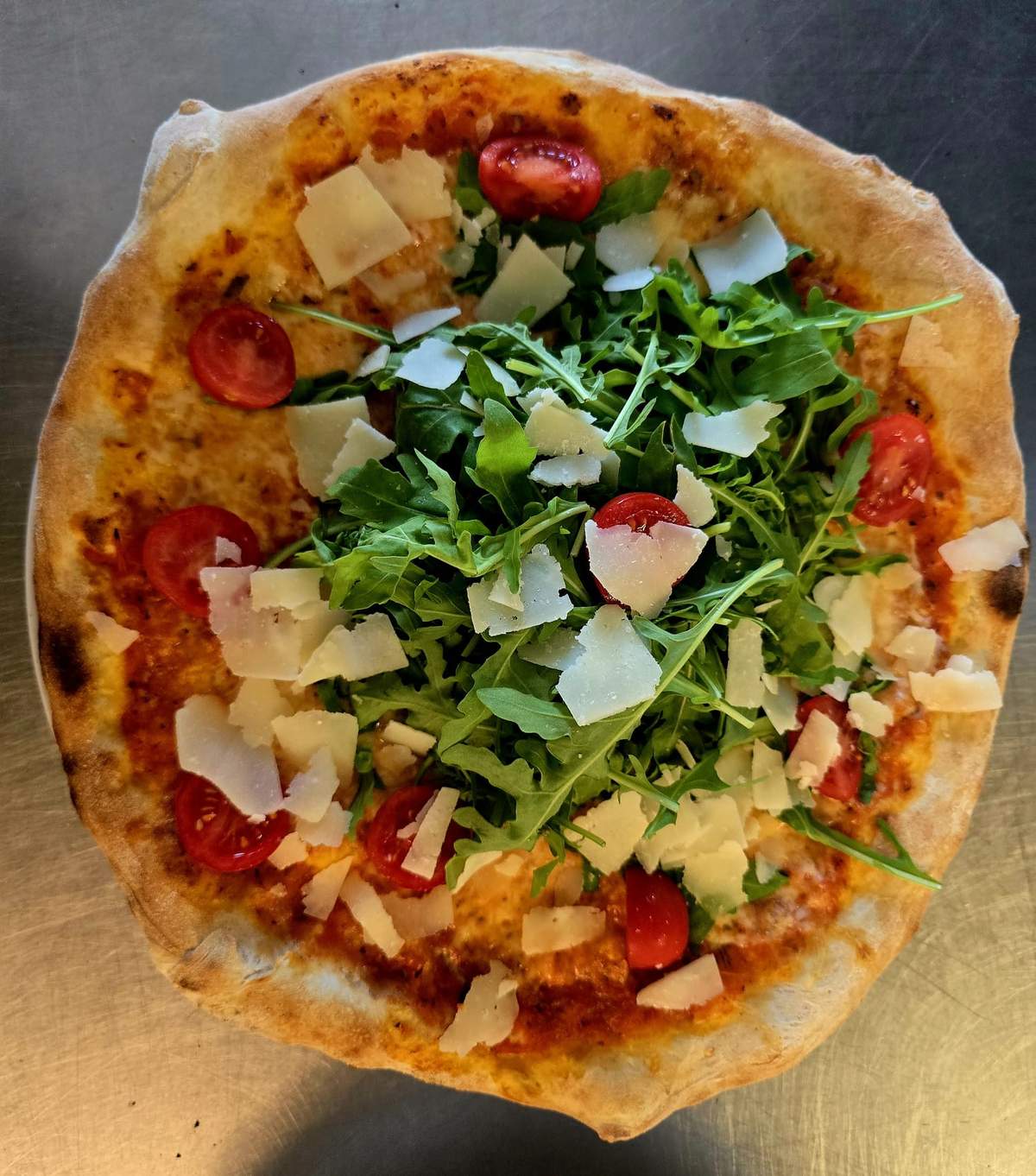 Pizza mit Rucola, Kirschtomaten und Parmesan